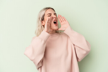 Young caucasian woman isolated on green background shouting excited to front.