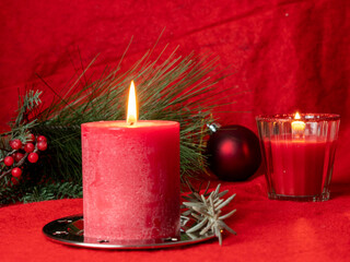Red Christmas candle and Christmas decorations on a red background.