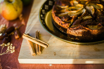 detail of cinnamon sticks on a wooden board next to an apple cake
