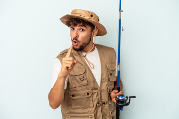 Young mixed race fisherman holding a rod isolated on blue background having an idea, inspiration concept.