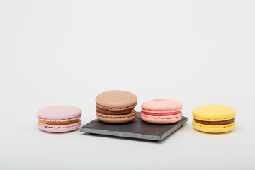 Colorful macaroons on grey mat on white background. Sweet bakery, copy space.