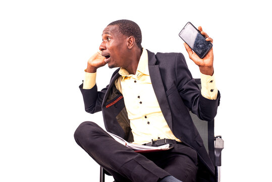 Surprised Business Man Sitting Looking Sideways And Holding Mobile Phone In Hand.