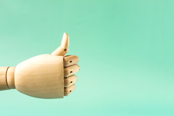 A wooden hand with a raised thumb on a green background of the space mine. The conceptual gesture is all right
