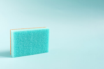 Colored porous sponge for cleaning and washing dishes close-up on a blue background copy space