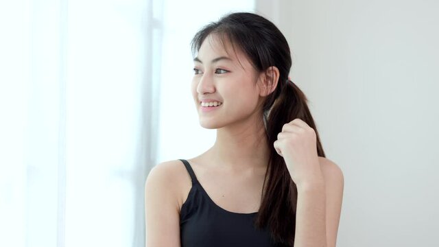 Young beautiful asian woman standing pose smiling look away outside. Sporty female workout and exercise wearing sport wear at home. Charming woman fitness relaxing after training and stretching.