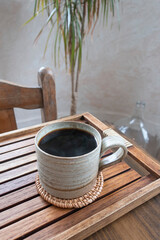 Cup of hot black coffee on rough wooden table.