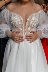 The bride is helped to put on a dress.