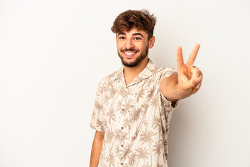 Young mixed race man isolated on grey background joyful and carefree showing a peace symbol with fingers.
