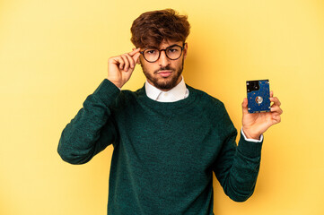 Young computerizer man isolated on yellow background pointing temple with finger, thinking, focused on a task.