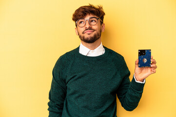Young computerizer man isolated on yellow background dreaming of achieving goals and purposes