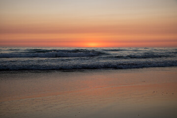 Rötlicher Sonnenuntergang am Meer mit Wellen in El Palmar Andalusien Spanien
