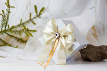 Obraz na płótnie Canvas A Christmas gift decorated with a beautiful bow on a light background with a twig, if. Selective focus. the concept of Christmas and New Year.