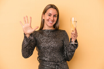 Young caucasian woman celebrating new year isolated on yellow background smiling cheerful showing number five with fingers.