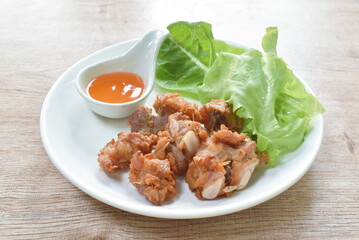 fried fermenting pork bone with garlic dipping chili sauce and fresh vegetable on plate
