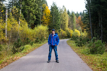 A man with a backpack stay on a forest road.
