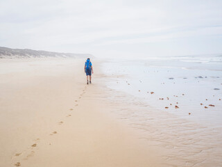 hiker walking relaxed on the beach of Brejo on the fishermen's route in Portugal on a cloudy day