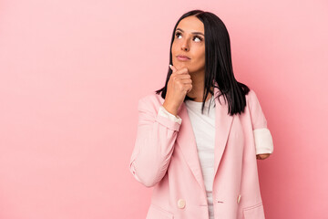 Young caucasian woman with one arm isolated on pink background looking sideways with doubtful and skeptical expression.
