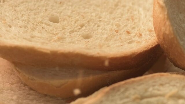 Bread crumbs falling on slices of white bread in slow motion on spinning plate