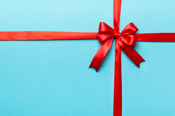 Top view of Red ribbon rolled and red bow isolated on colored background. Flat lay with copy space