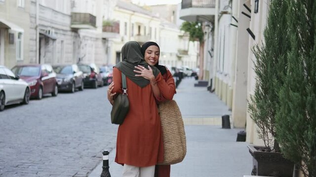 Two positive Muslim women hugging at the meeting outdoors