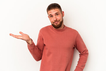 Young caucasian man with diastema isolated on white background doubting and shrugging shoulders in...