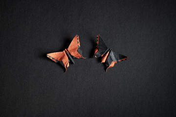 Couple of origami orange and black butterflies on a black texture background. Pair of isolated...