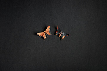 Couple of origami orange and black butterflies on a black texture background. Pair of isolated...