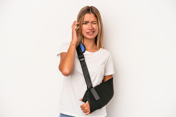 Young caucasian woman with broken hand isolated on white background covering ears with hands.