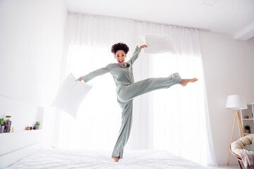 Full length body size view of attractive cheerful ecstatic crazy girl dancing on bed fooling at light white home indoors