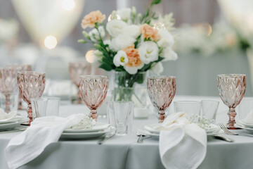 banquet table is decorated with plates, cutlery, glasses and flower arrangements