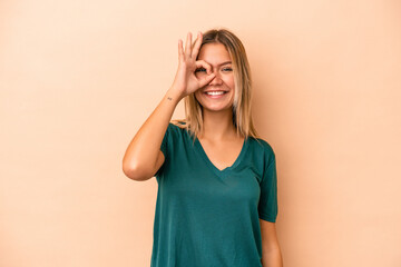 Young caucasian woman isolated on beige background excited keeping ok gesture on eye.