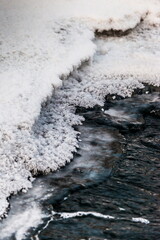 Icicles and frost on a snow-covered frozen river