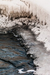 Icicles and frost on a snow-covered frozen river