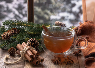 Steaming hot cup of tea with winter background