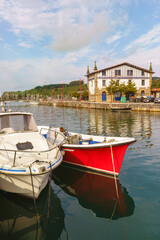 Fototapeta na wymiar Side view of fishing boats resting in Narrondo river in the spanish city of Zumaia. Horizontal view of fishing town landscape in the Vasque country. Travel destination in Spain.