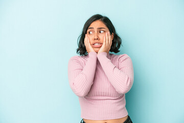 Young latin woman isolated on blue background scared and afraid.