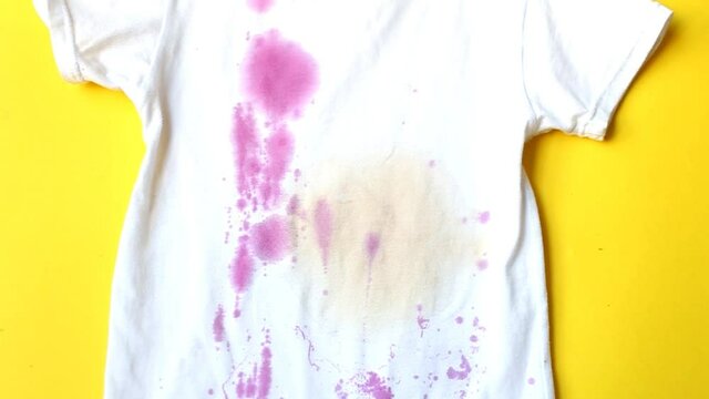 dirty stains on a white T-shirt from garnet and drinks. pomegranate seeds fly into the shirt on yellow background.