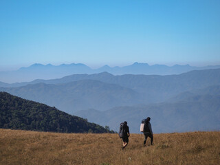 Obraz premium Two backpacker are trekking along the way at Monjong Chiangmai with beautiful view of mountain range