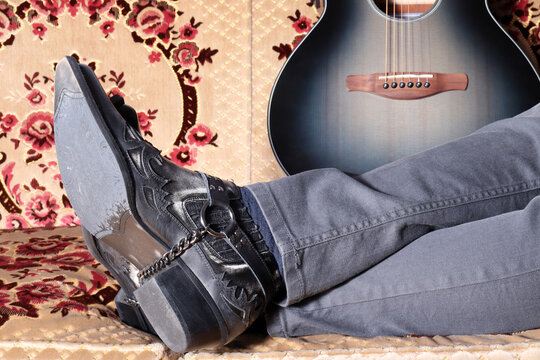 Cowboy boots and guitar. He is resting.