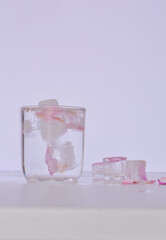 Rose petals ice cube in a glass of water and melting on the side