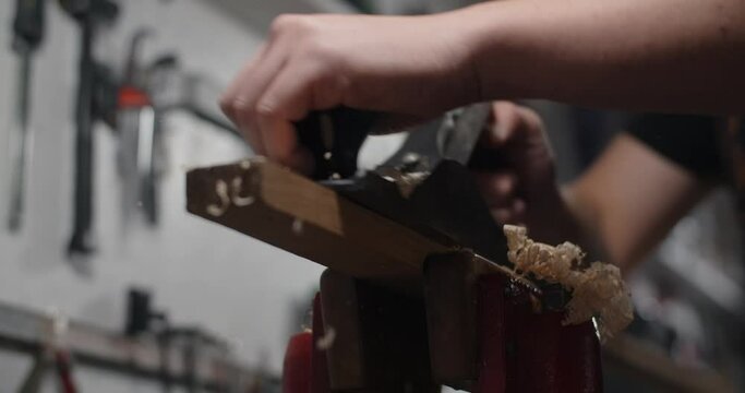 Luthier uses hand plane for wood processing at his workshop. Guitar maker uses jack plane in slow motion, 4k 60p Prores HQ