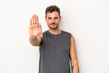 Young caucasian man isolated on white background standing with outstretched hand showing stop sign, preventing you.