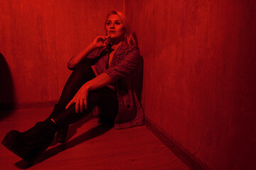 blonde girl in a jacket in a room with a red light.