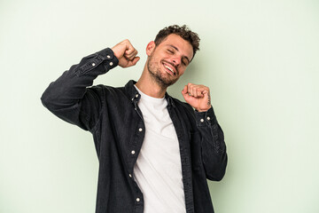 Naklejka premium Young caucasian man isolated on green background celebrating a special day, jumps and raise arms with energy.