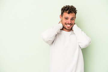 Young caucasian man isolated on green background touching back of head, thinking and making a choice.