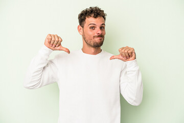 Young caucasian man isolated on green background feels proud and self confident, example to follow.