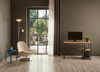 Grey living room office, monitor, chair vase of green plant in front of the window garden view.