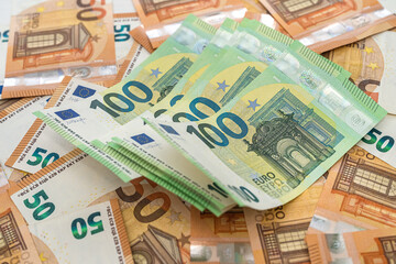 new 50 euro banknotes are scattered on the table and on them lie acuranto 100 euro banknotes