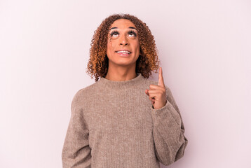 Young latin transsexual woman isolated on pink background indicates with both fore fingers up...