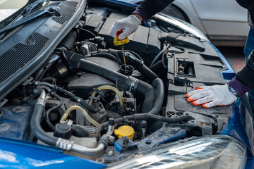 mechanic man with strong hands in special gloves repairs a car with an open hood